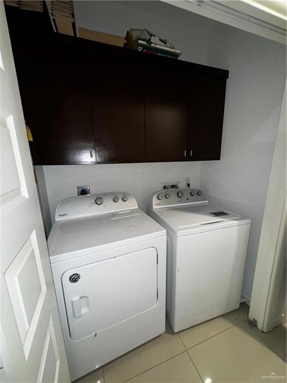 Washroom featuring hookup for a washing machine, washing machine and clothes dryer, cabinets, and light tile flooring