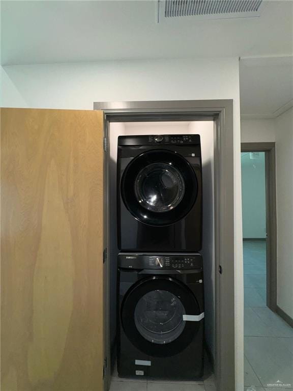 Laundry room featuring stacked washing maching and dryer and tile floors
