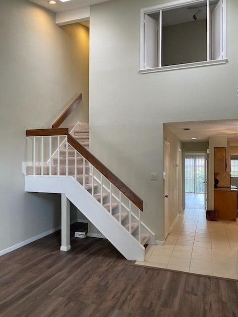 Staircase featuring a high ceiling and wood finished floors