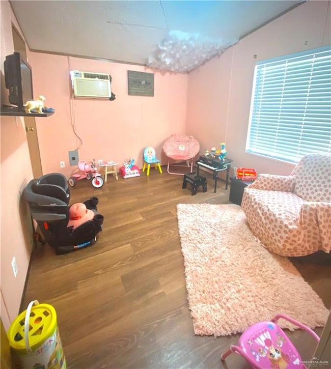 Game room with a wall unit AC, wood finished floors, and vaulted ceiling