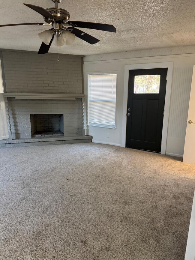 Unfurnished living room featuring ceiling fan, a f