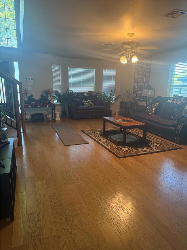 Living room featuring ceiling fan, visible vents,