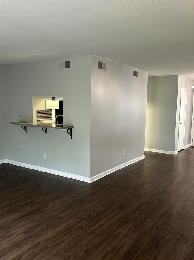 Empty room featuring dark wood finished floors and baseboards