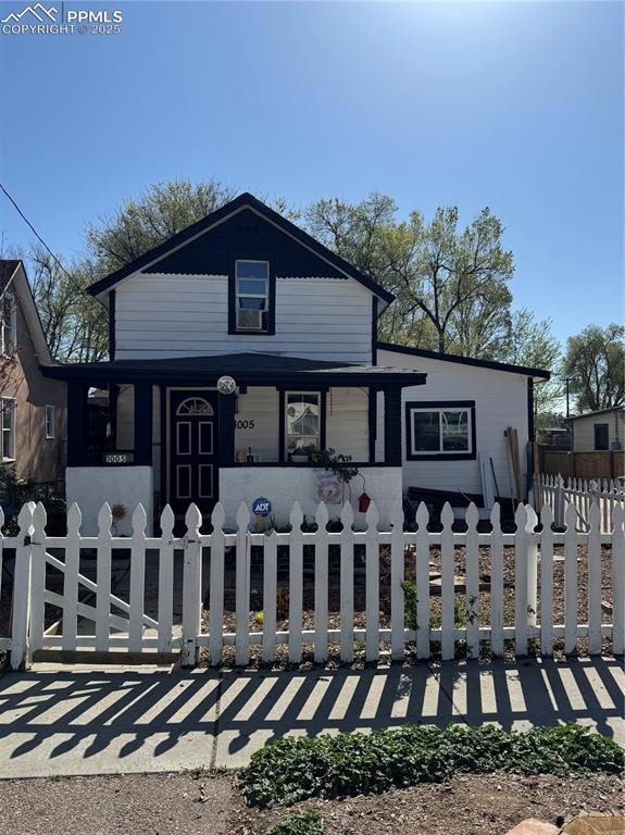 View of front of property with covered porch and a fenced front yard