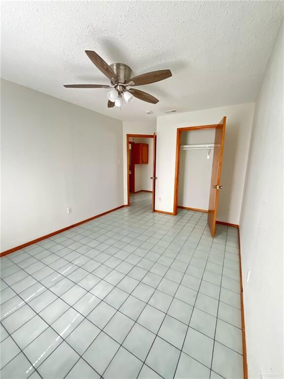 Unfurnished bedroom featuring a closet, a textured ceiling, and a ceiling fan