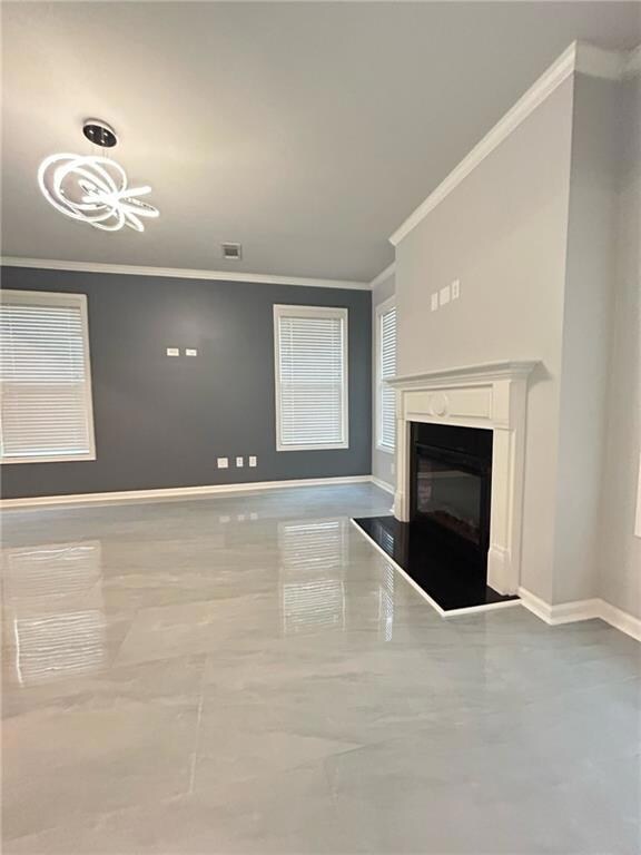 Unfurnished living room featuring ornamental molding, a glass covered fireplace, and a chandelier