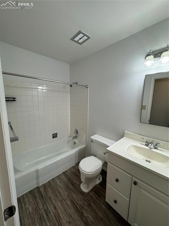 Bathroom with wood finished floors, toilet, vanity, and shower / bath combination