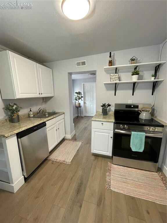 Kitchen with white cabinetry, stove, dishwashing m