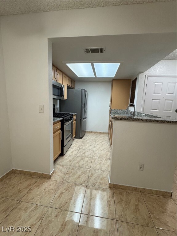 Kitchen with visible vents, baseboards, dark stone