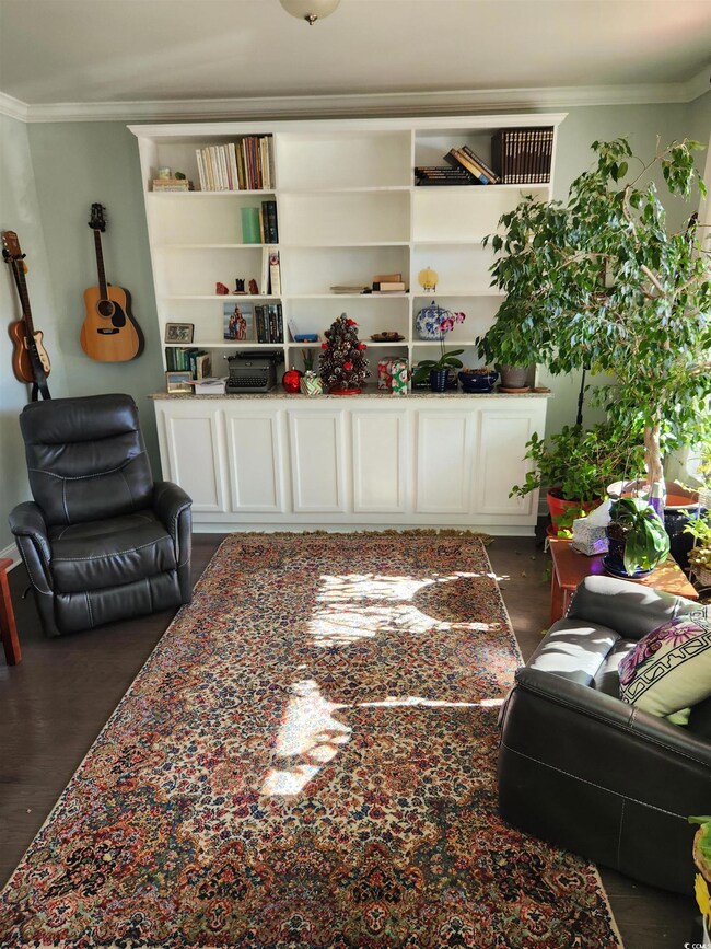 Living room featuring ornamental molding and dark wood-type flooring