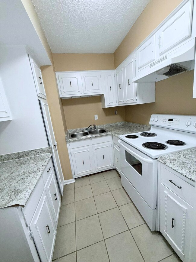 Kitchen featuring white cabinetry, white electric 