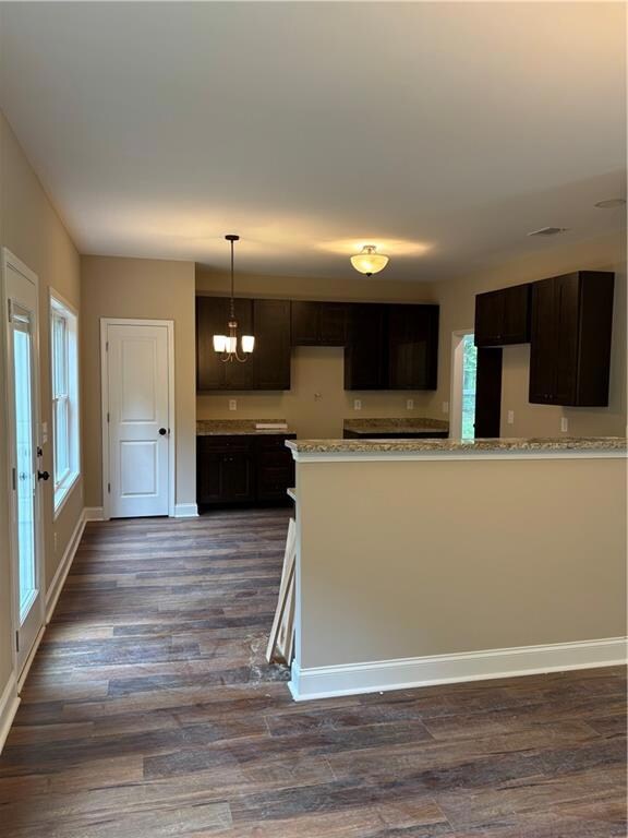 Kitchen with dark brown cabinets, dark wood-style flooring, a chandelier, and decorative light fixtures