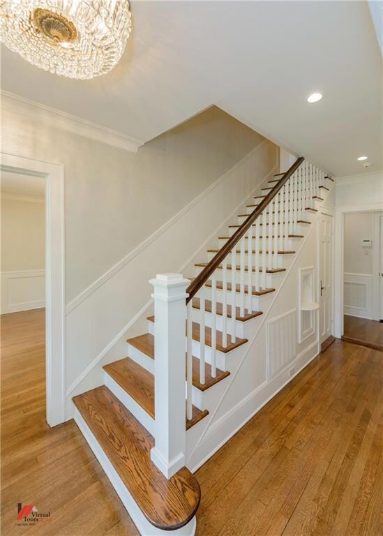 Refinished wood floors and flowing staircase greet