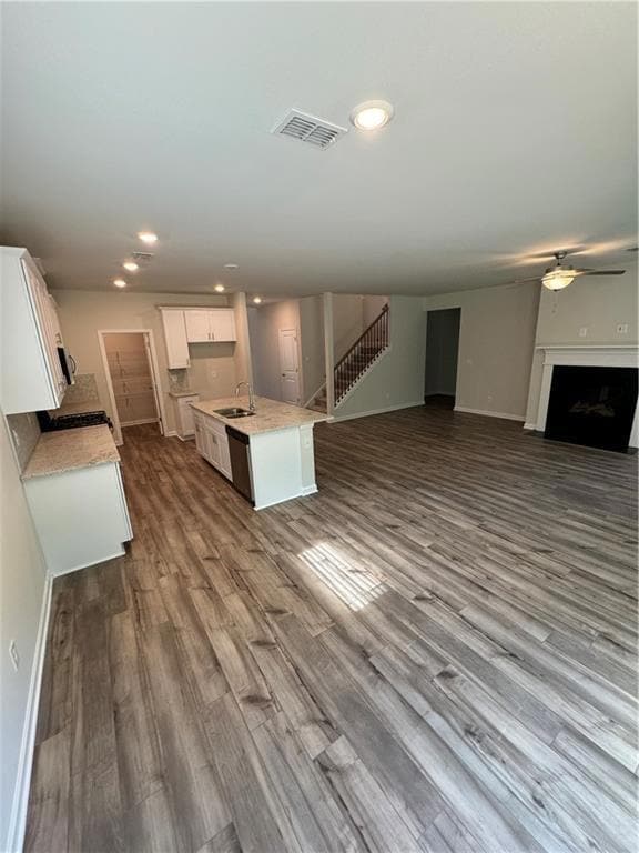 Unfurnished living room featuring a ceiling fan, dark wood-style floors, recessed lighting, stairway, and a fireplace