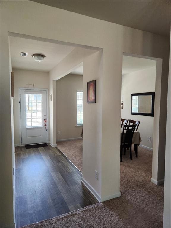 Carpeted entryway with visible vents, baseboards, 