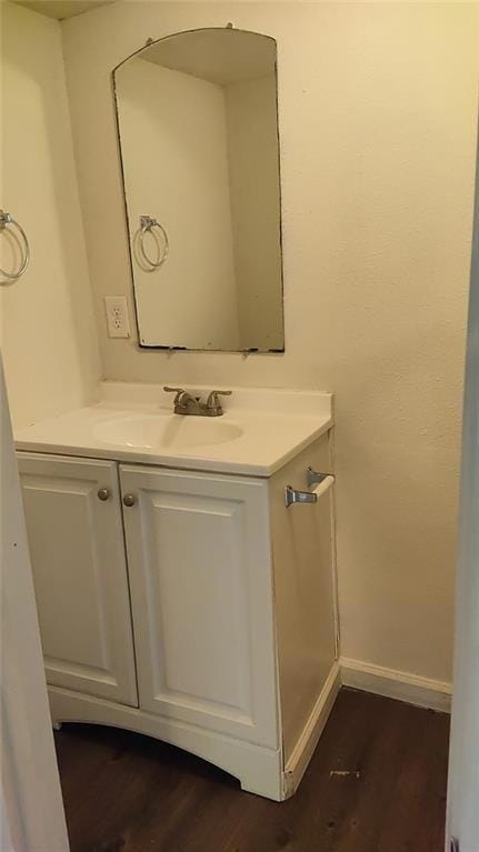 Bathroom with vanity, baseboards, and wood finish