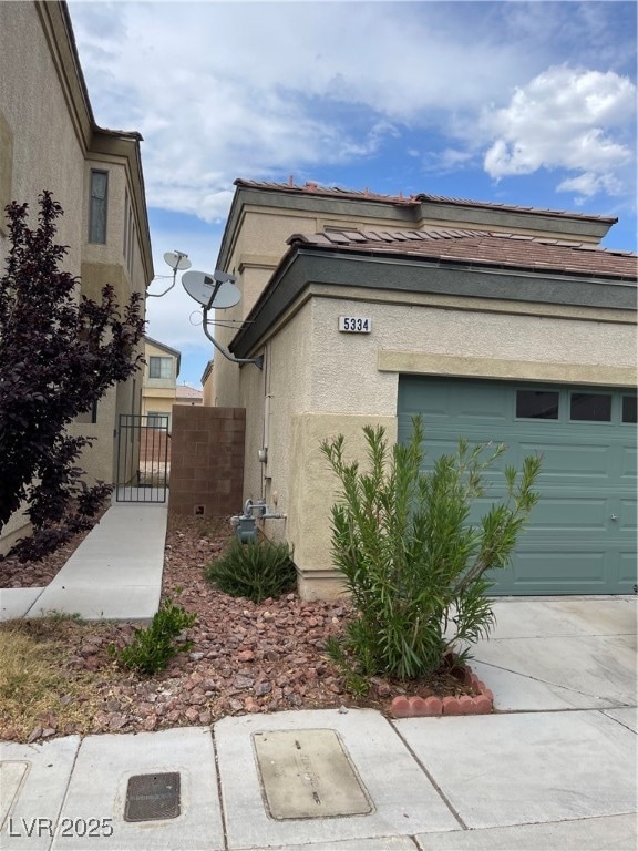 View of side of home with stucco siding and a gate