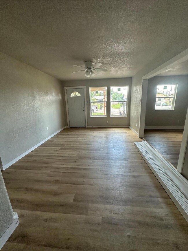 Empty room with a textured ceiling, dark wood-type