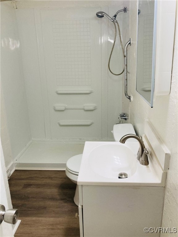 Bathroom featuring a shower stall, vanity, toilet,