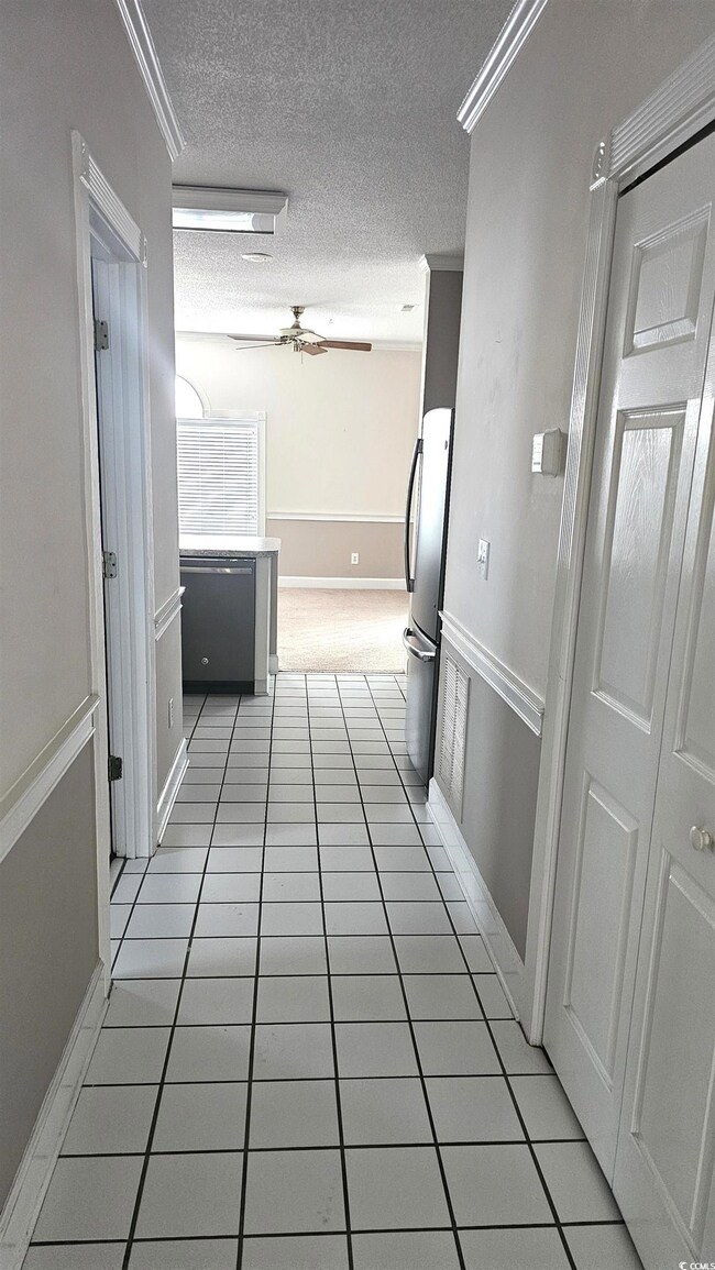 Corridor featuring a textured ceiling, light tile 