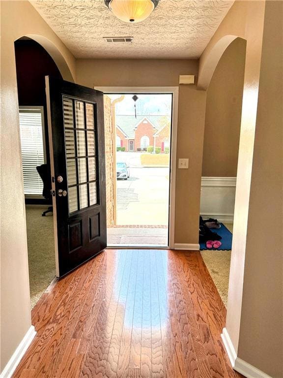 Foyer featuring arched walkways, wood finished flo