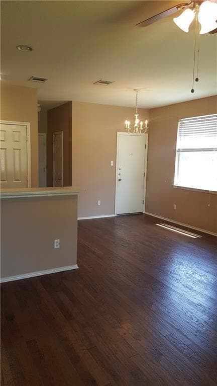 Empty room with dark wood-style flooring, baseboa