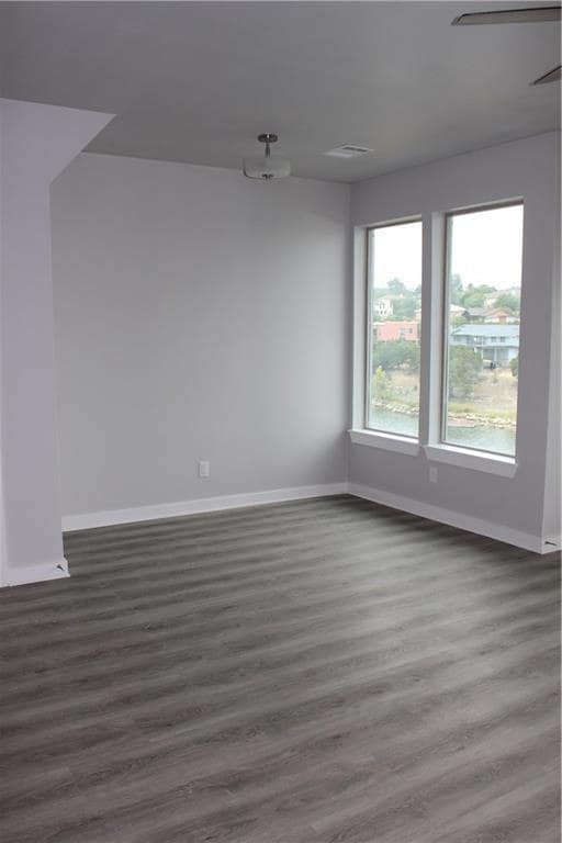 Unfurnished room featuring baseboards and wood fi