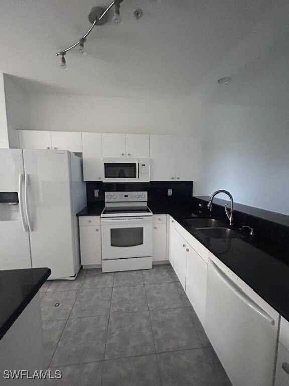 Kitchen featuring sink, white cabinets, dark tile