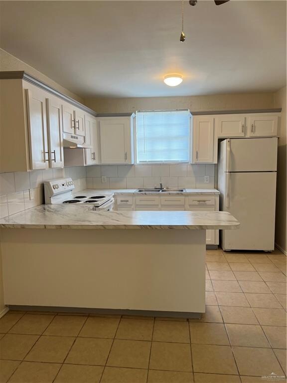 Kitchen featuring refrigerator, stove, a sink, a peninsula, and extractor fan