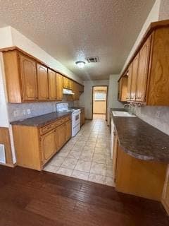 Kitchen with brown cabinetry, dark countertops, an