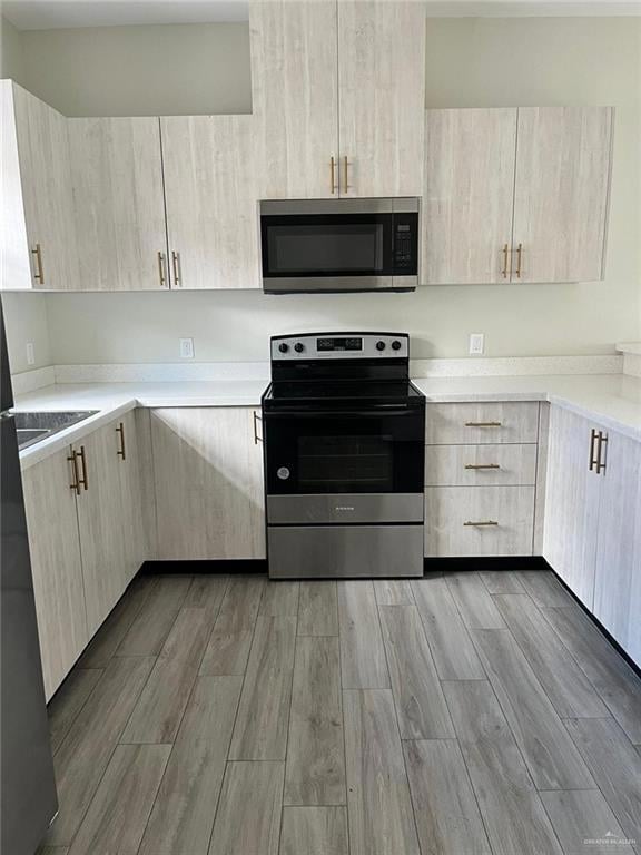 Kitchen with appliances with stainless steel finishes, light wood-style floors, and light brown cabinetry