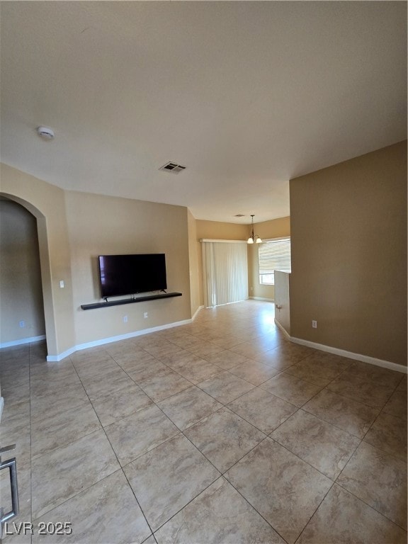 Unfurnished living room with arched walkways, tile
