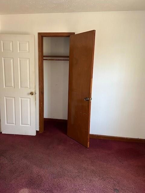 Unfurnished bedroom with a closet and dark carpet
