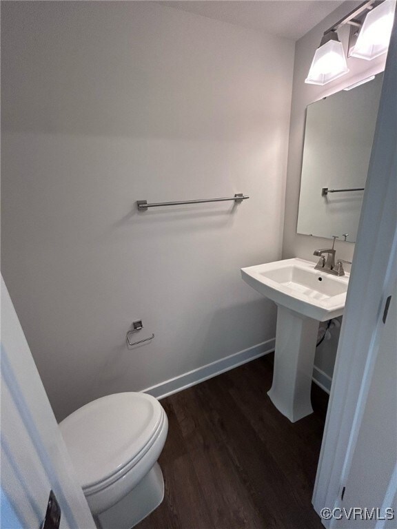 Half bath featuring wood finished floors, toilet,