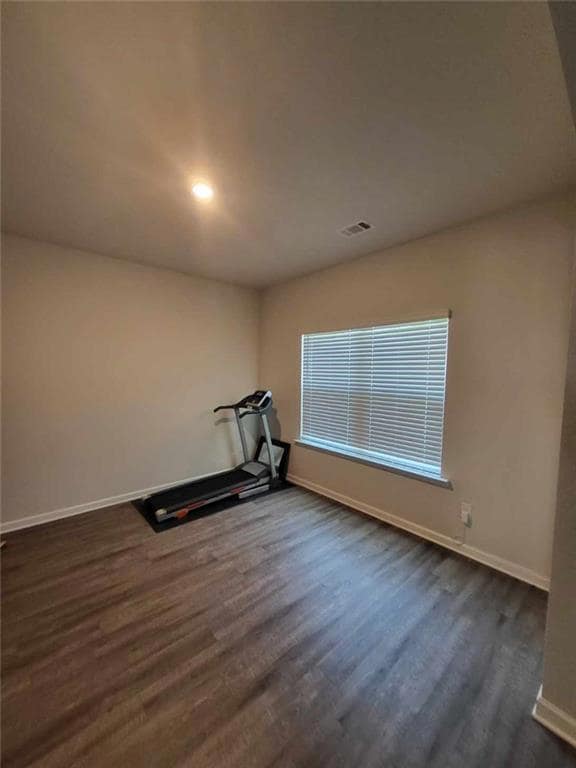 Workout room with dark wood-style floors, baseboards, and recessed lighting