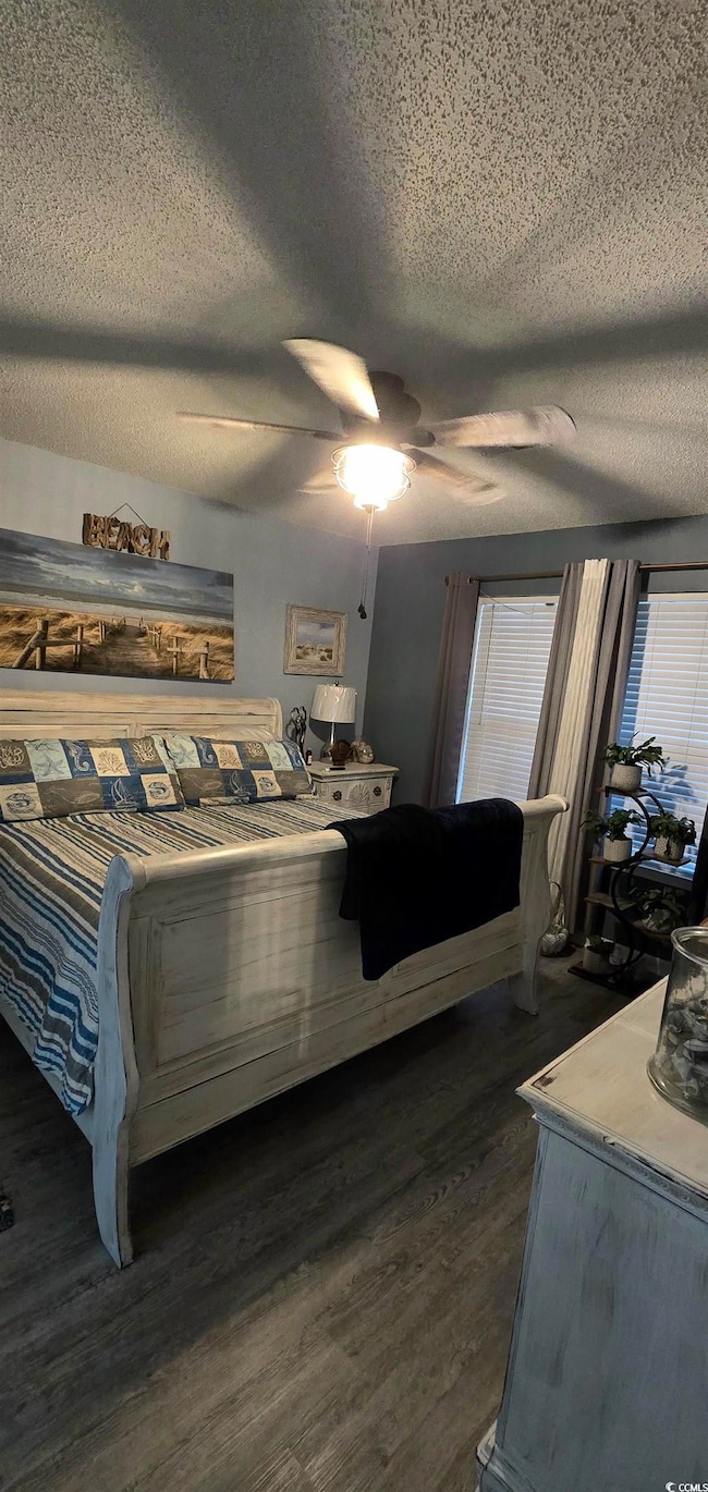 Bedroom with dark wood-type flooring, a textured c