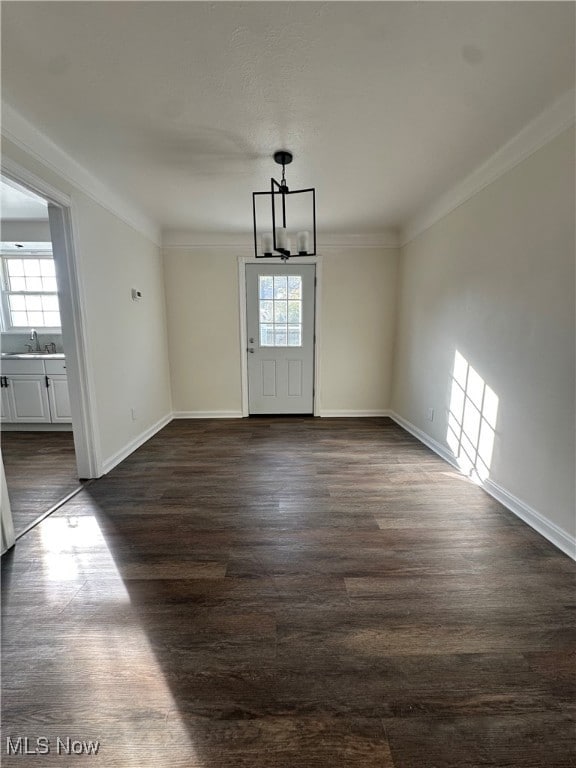 Unfurnished dining area featuring dark wood-type flooring and crown molding