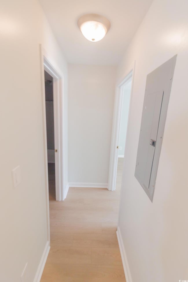 Hall with electric panel and light wood-style floors