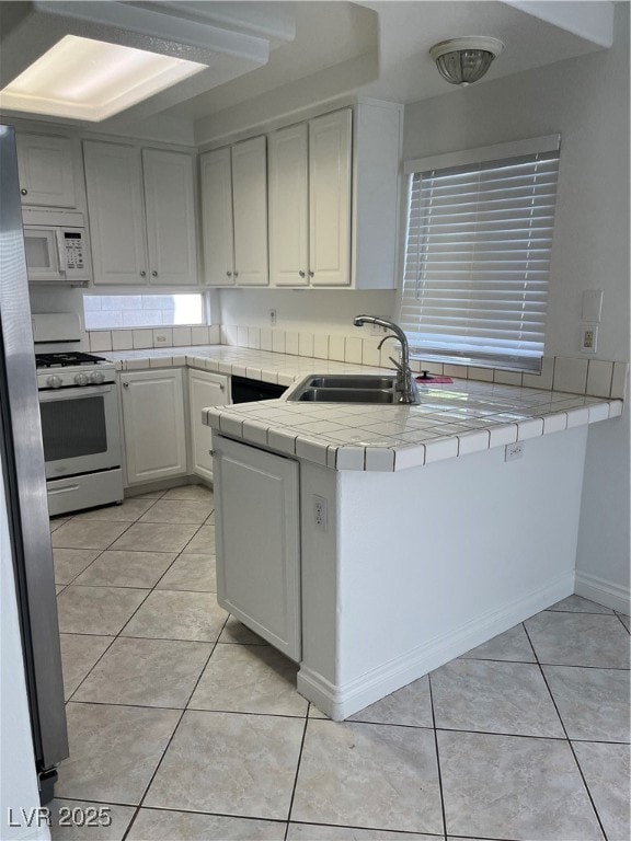 Kitchen with a sink, tile counters, stove, white c
