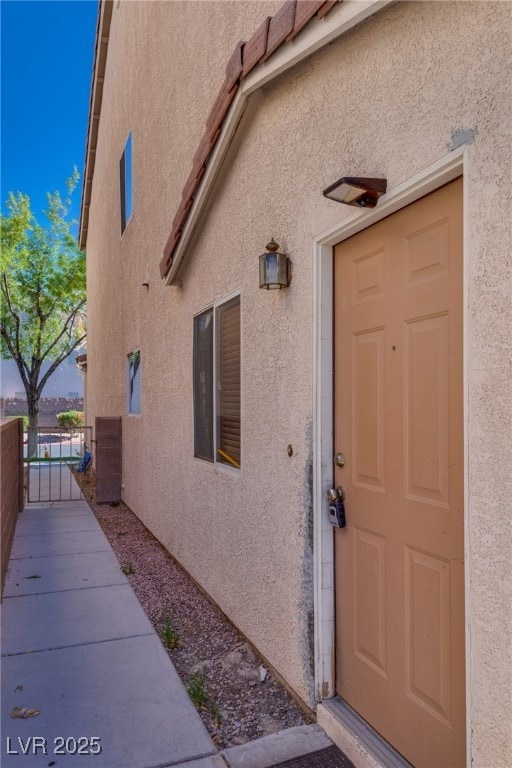 Property entrance with stucco siding and a gate
