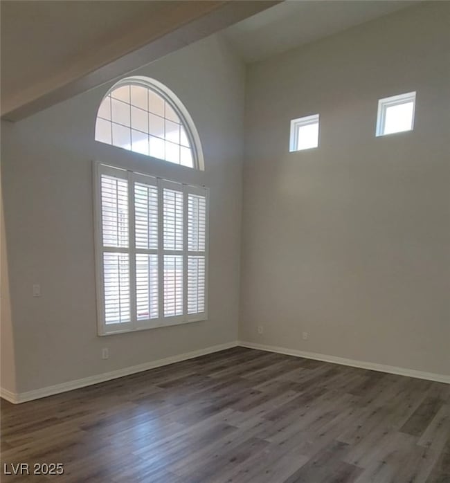 Spare room featuring dark wood-type flooring and b