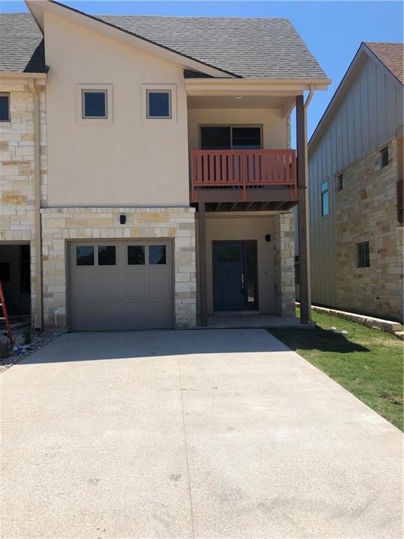 Back of property with stone siding, a balcony, co