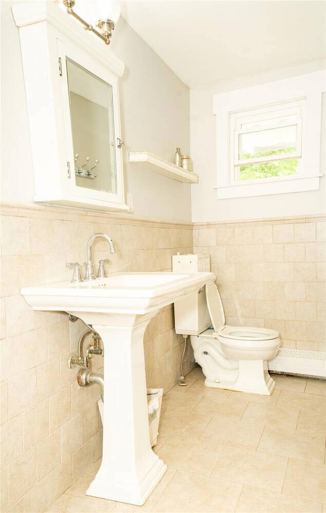 Bathroom with tile walls, tile patterned floors, and wainscoting