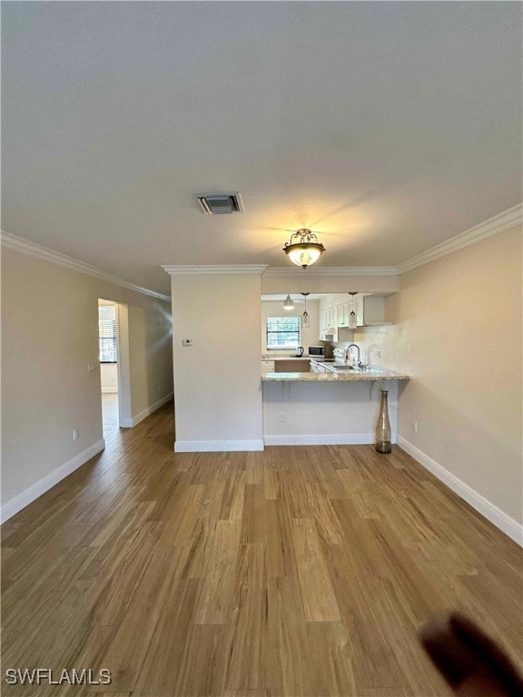 Unfurnished living room featuring light wood-type flooring and crown molding