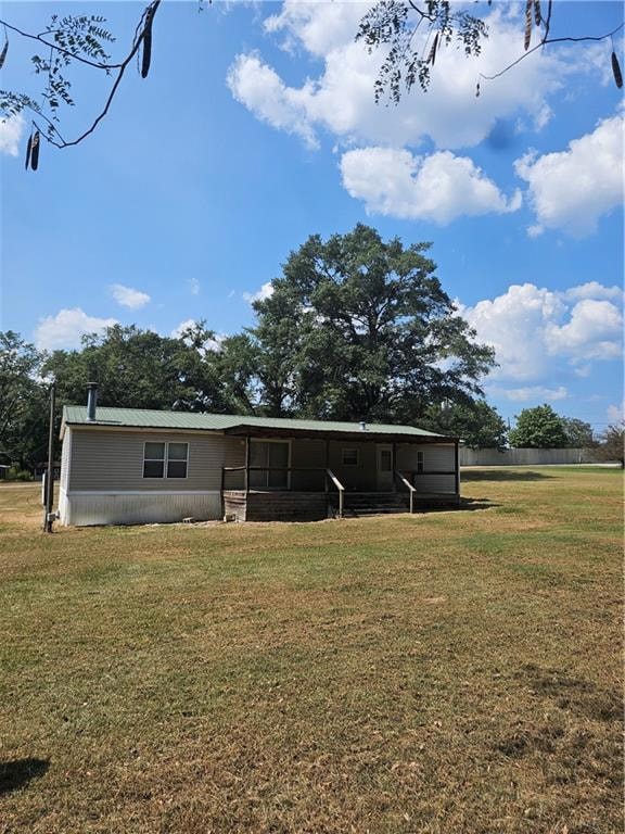 View of rear of home featuring a back yard lawn, a metal roof, and covered porch
