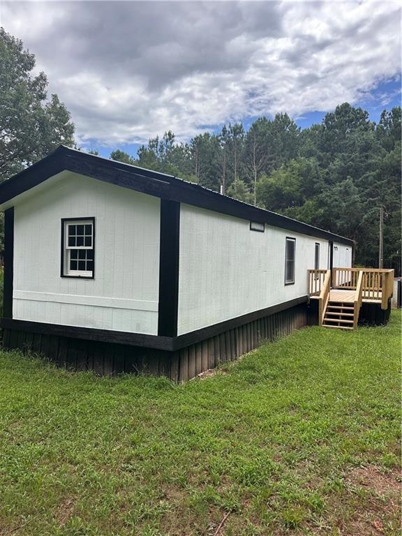 View of side of home with a deck and a lawn