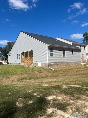 Rear view of house with crawl space and a lawn
