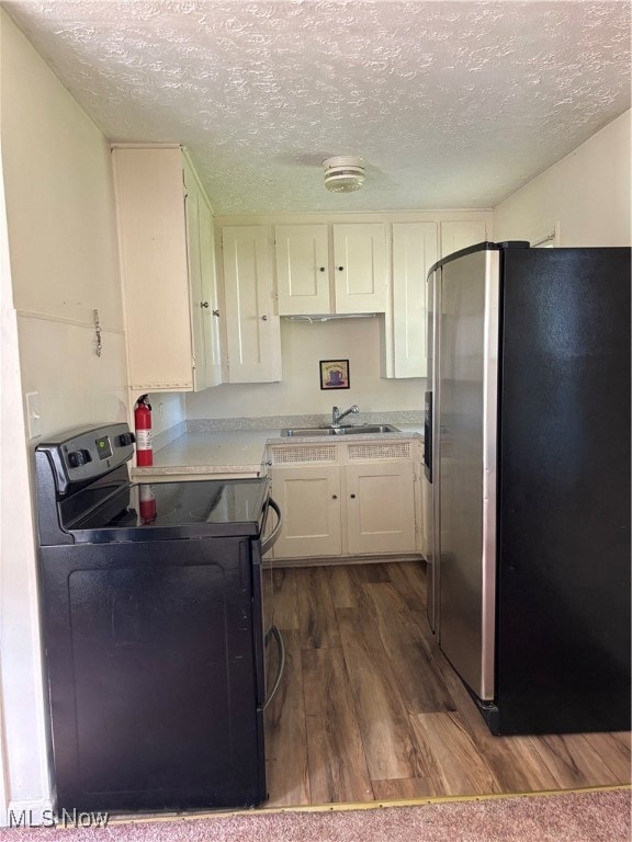 Kitchen featuring refrigerator, range, dark wood-style flooring, a textured ceiling, and white cabinetry
