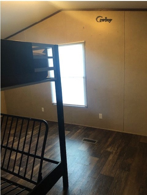 Unfurnished room featuring dark wood finished floors and lofted ceiling