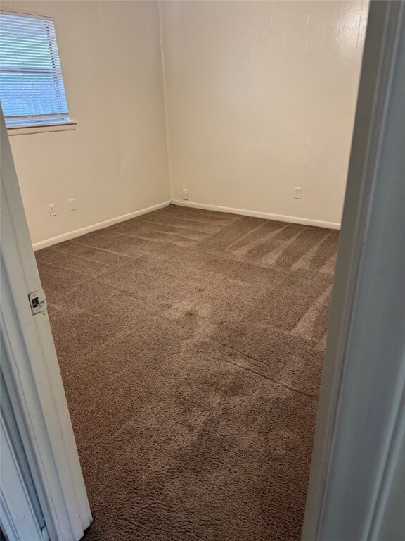 Unfurnished room featuring dark colored carpet and